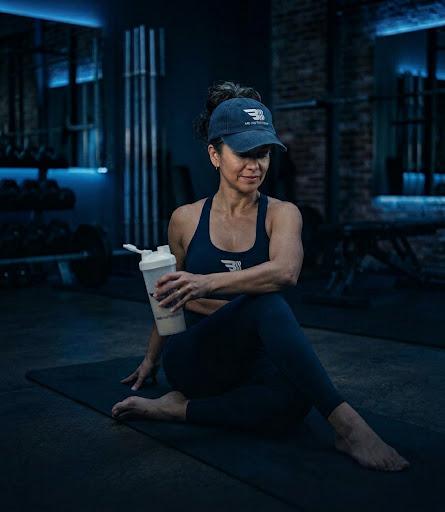 Adulto estirando después de entrenar con un shaker en la mano